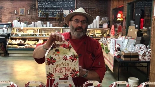 Mike The Wurstmeister holding a Christmas gift box available in Hermann Wurst Haus