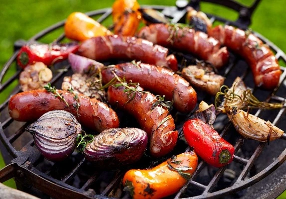 Bratwursts on a grill with vegetables