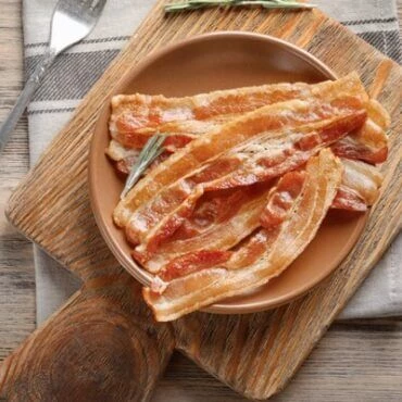 Bacon in a plate on a wooden chopping board